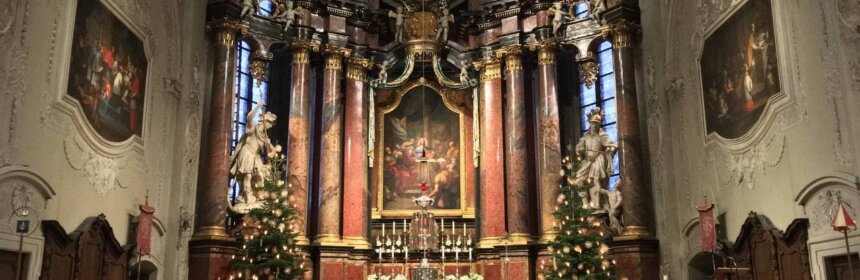 Blick auf den Hochaltar mit geschmückten Christbäumen zu Weihnachten